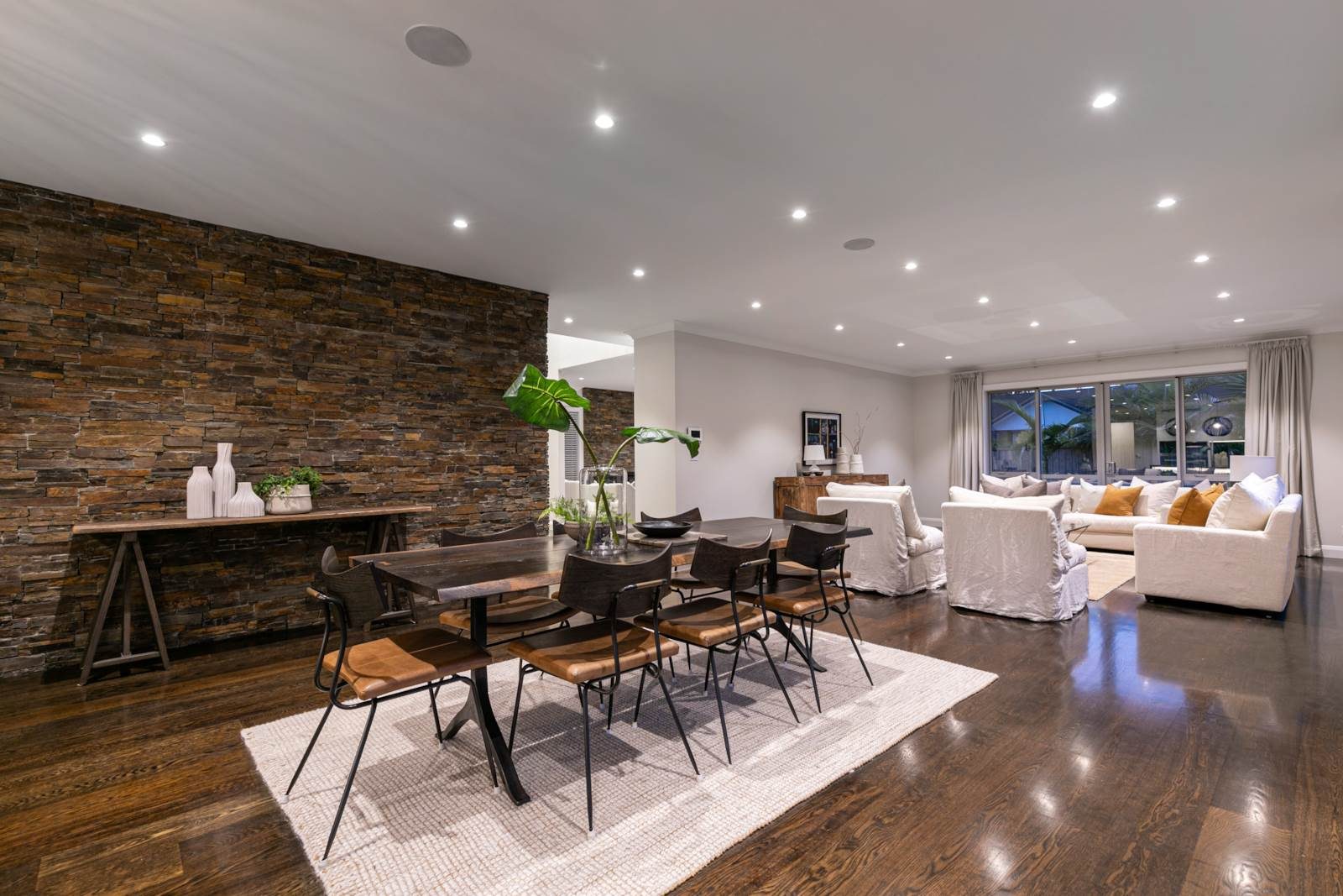 Open-plan living and dining space with a stone feature wall