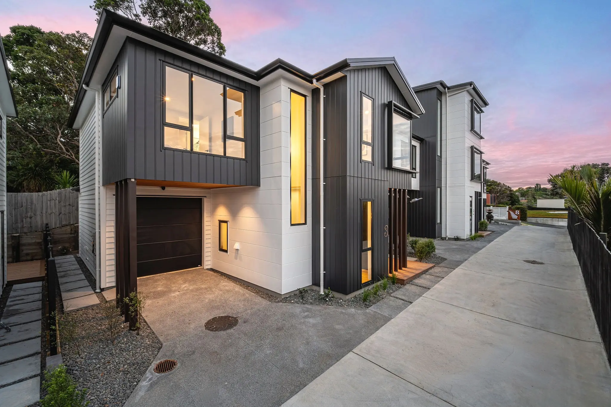 Twilight view along the internal driveway with contrasting black and white façades