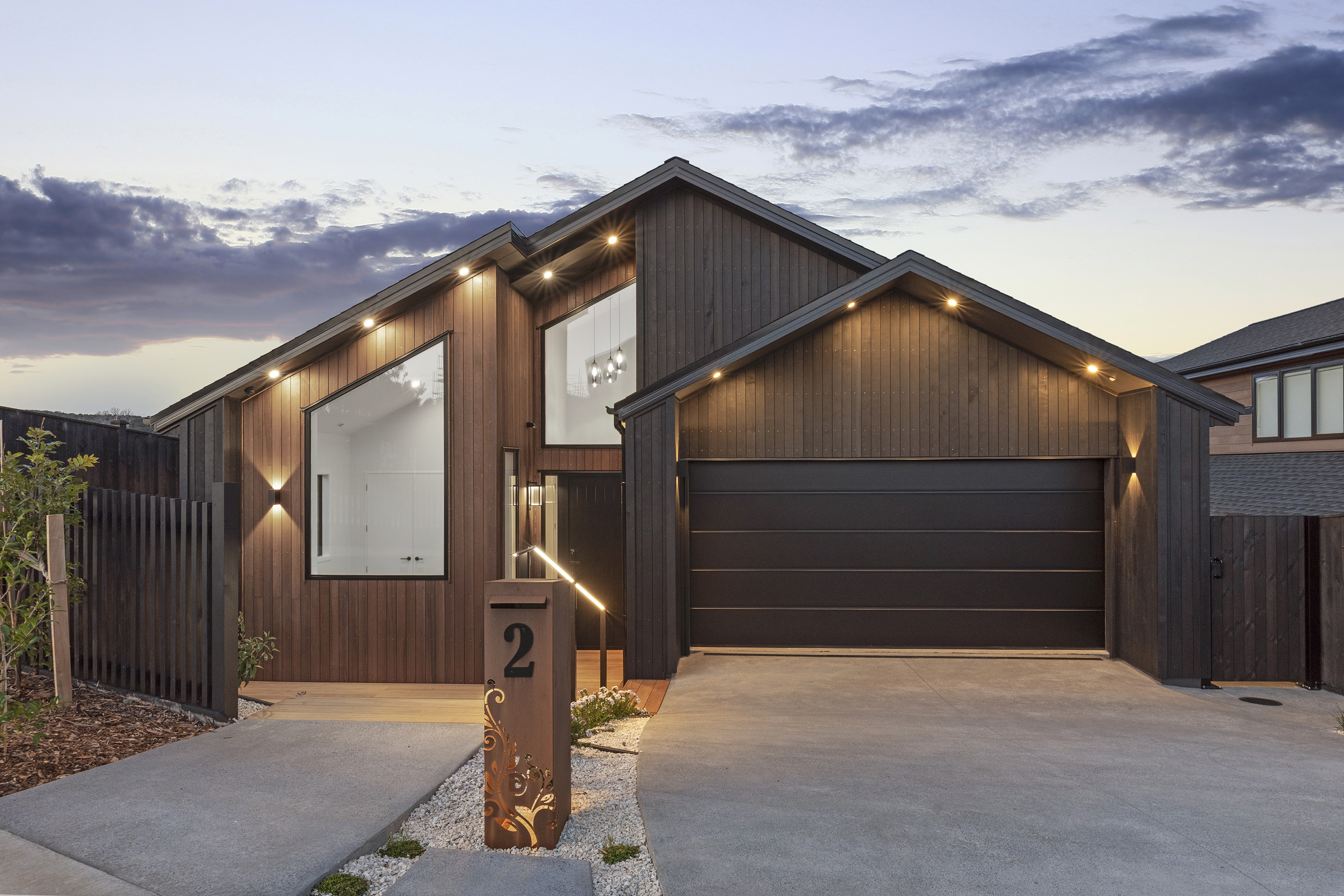 Twilight view of the timber-clad Ara Hills Residence with gabled roof forms