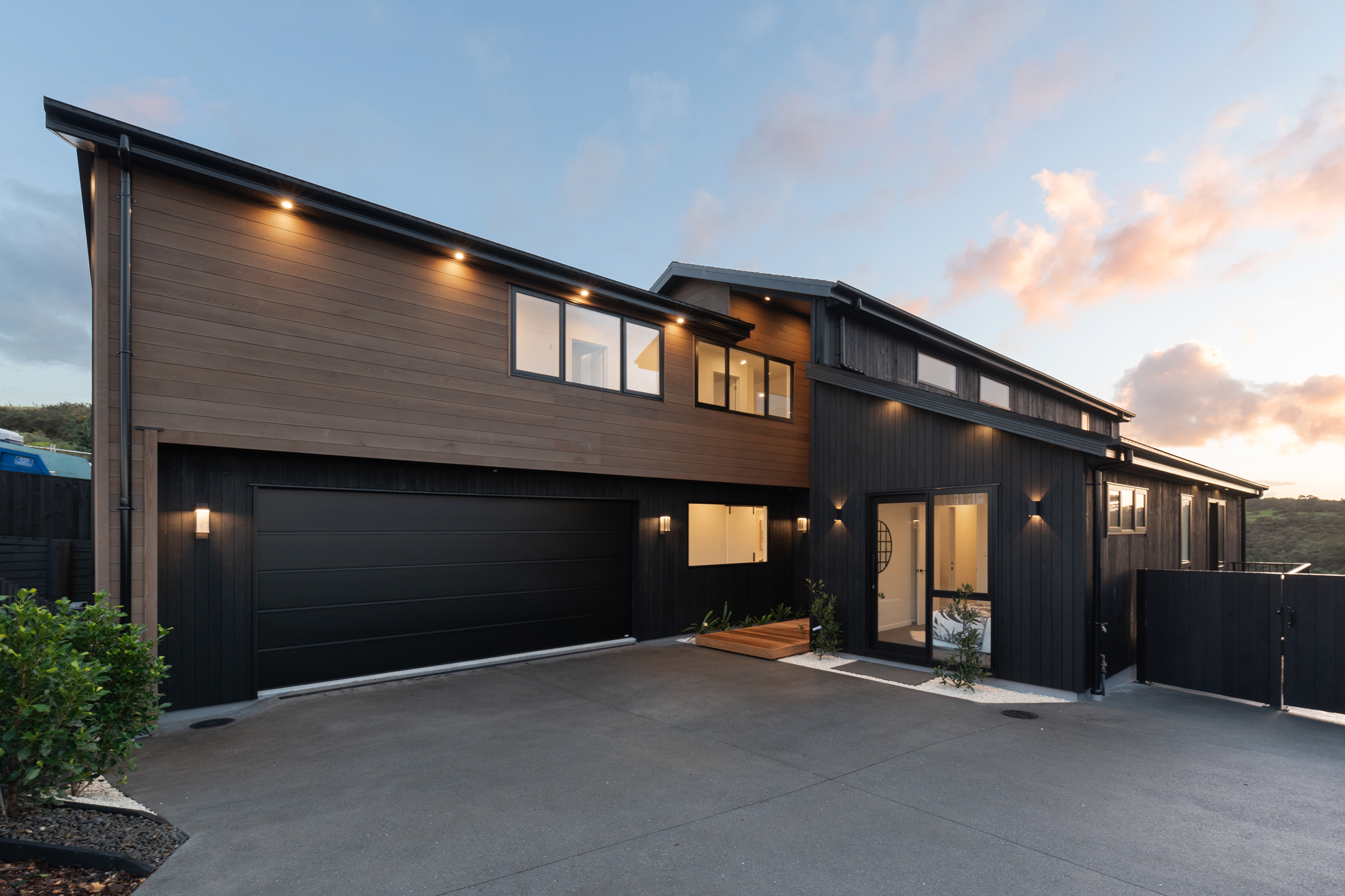 Twilight view of 22 Kikorangi Drive with dark cladding and warm timber detailing