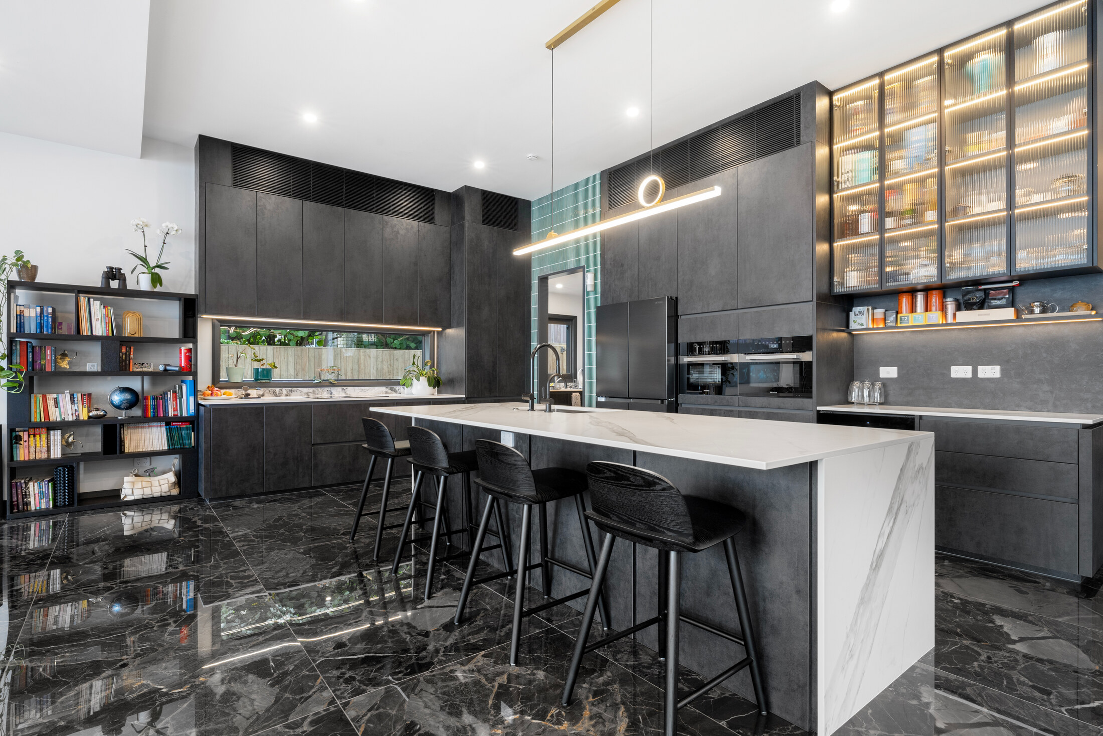 Kitchen and bar area with dark joinery and illuminated display shelving
